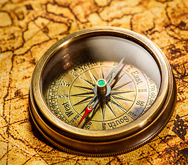 Image showing Vintage compass lies on an ancient world map.