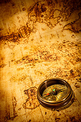 Image showing Vintage compass lies on an ancient world map.