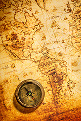 Image showing Vintage compass lies on an ancient world map.