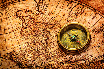 Image showing Vintage compass lies on an ancient world map.