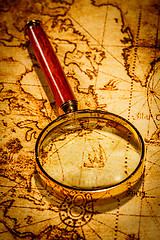 Image showing Vintage magnifying glass lies on an ancient world map