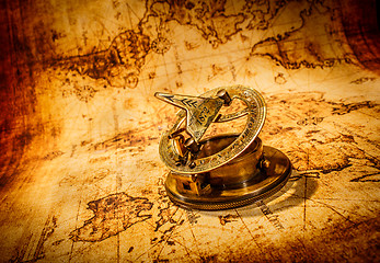 Image showing Vintage compass lies on an ancient world map.