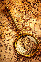 Image showing Vintage magnifying glass lies on an ancient world map