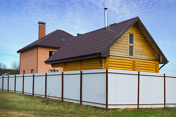 Image showing Brick and wooden house behind a fence