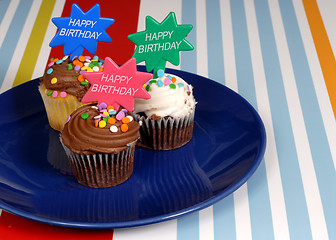 Image showing Three chocolate frosted cupcakes on a blue plate with 