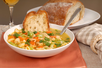 Image showing A bowl of chicken noodle soup with rustic bread and a glass of w