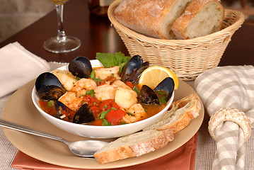 Image showing Bowl of delicious seafood soup with wine and rustic bread