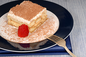 Image showing A piece of tiramisu dusted with cocoa with a fork on a blue plat