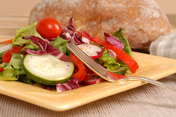 Image showing Side view of a healthy salad on a yellow plate with rustic bread