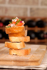 Image showing Stack of bruschetta with wine rack in background