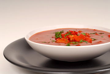 Image showing Tomato, red pepper, basil soup in white bowl with light gray bac