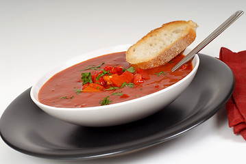 Image showing Tomato, red pepper, basil soup in white bowl with bread and spoo