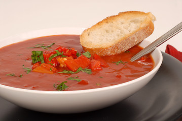 Image showing Side view of a bowl of tomato, red pepper and basil soup with br