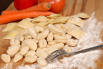 Image showing Gnocchi and ravioli on a floured cutting board with vegetables i