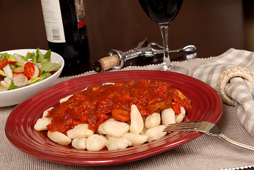 Image showing Potato gnocchi with marinara sauce with a salad and wine