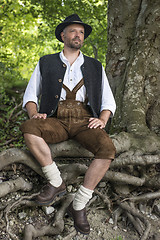 Image showing Seated man in traditional Bavarian costumes in forest