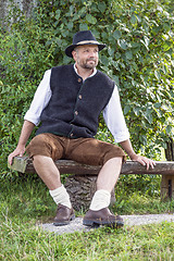 Image showing Seated man in traditional Bavarian costumes and black hat