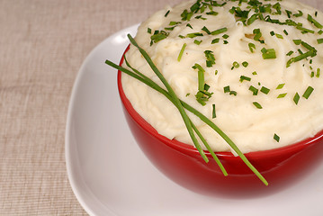 Image showing Closeup of creamy mashed potatoes with chives in a red bowl