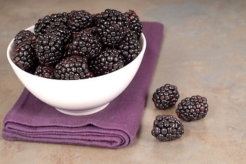 Image showing Blackberries in a white bowl on a purple napkin with blackberrie