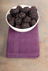 Image showing Vertical view of blackberries in a white bowl on a purple napkin