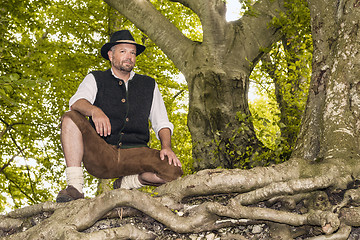 Image showing Kneeling man in traditional Bavarian costumes in forest