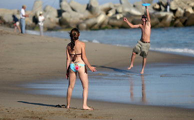 Image showing Couple playing frisbee on the beach