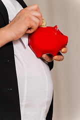 Image showing Pregnant business woman with piggy bank