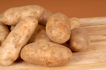 Image showing Several russet potatoes piled on a cutting board