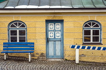 Image showing Yellow house with blue bench