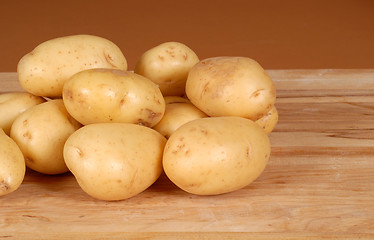 Image showing Several white potatoes piled on a cutting board
