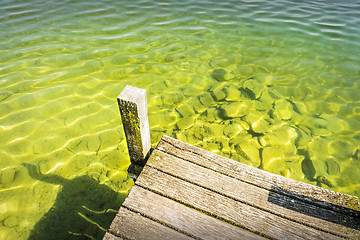 Image showing Part of a jetty over a lake of weathered wood with green-blue wa