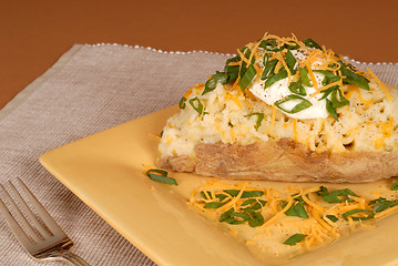 Image showing A twice baked potato with scallions, cheese and sour cream