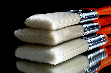 Image showing three stacking paint brushes with reflection on table