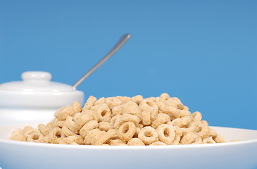 Image showing Oat cereal in white bowl with sugar bowl on blue background