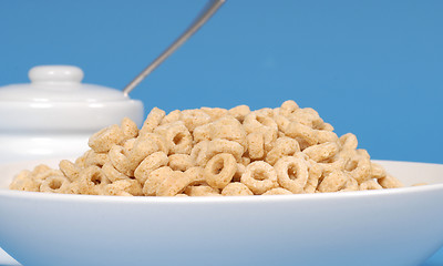 Image showing Bowl of oat cereal with sugar bowl on blue background
