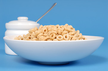 Image showing A bowl of oat cereal with sugar bowl on blue background