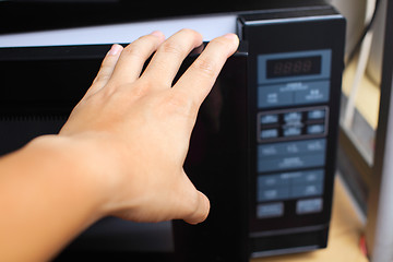 Image showing Hand using microwave oven