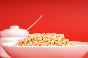 Image showing A bowl of oat cereal with sugar bowl on red background