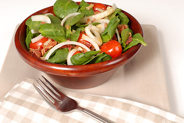 Image showing Fresh spinach salad in a brown wooden bowl
