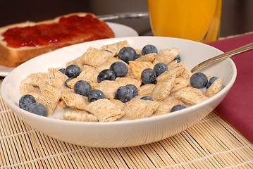 Image showing A bowl of wheat cereal with blueberries, toast and orange juice