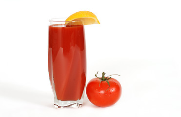 Image showing Glass of tomato juice with lemon wedge and tomato next to glass