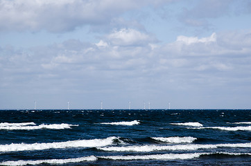 Image showing Waves with windmills in the horizon