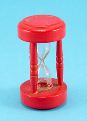 Image showing broken red sand glass clock on blue background 