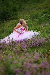 Image showing Young beautiful bride sitting at a forest glade