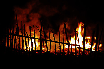 Image showing Fire in countryside with wooden fence in foreground