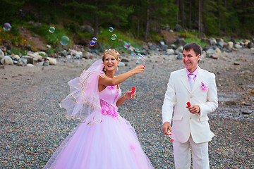 Image showing Bride and groom having fun with soap bubbles