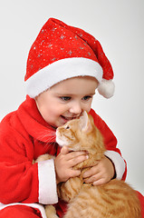 Image showing Christmas toddler child plays with a cat