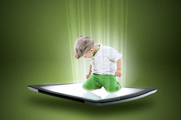 Image showing Little boy on a tablet with beams of data