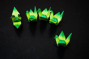 Image showing A group of green paper birds on dark background