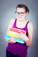 Image showing Silly smiling schoolgirl with glasses and lots of books